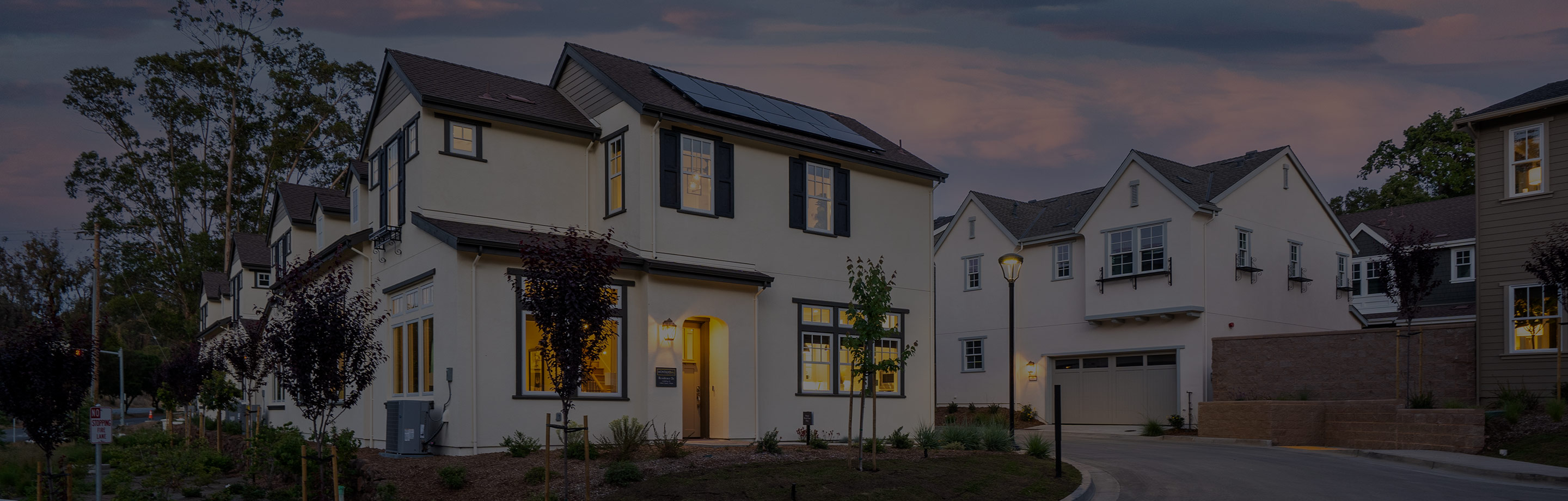 Two-story Mediterranean-style home by SummerHill Homes illuminated at dusk, featuring arched entryways and a tiled roof.