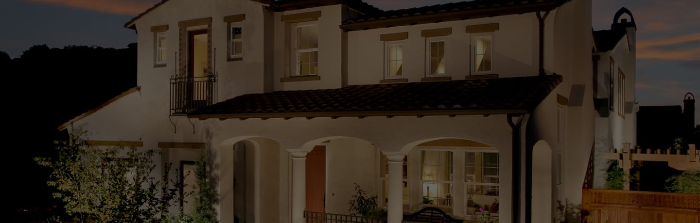 Two-story Mediterranean-style home by SummerHill Homes illuminated at dusk, featuring arched entryways and a tiled roof.